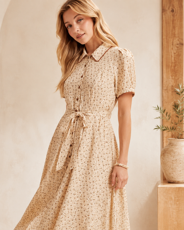 Close view of the floral print, collar, buttons and matching tie waist on a buttercream maxi dress